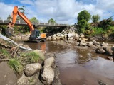 Digger under bridge in creek