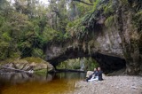 Couple sitting by a limestone arch and river.